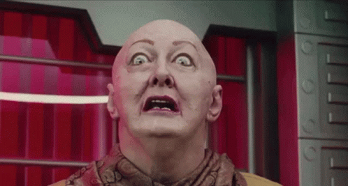 Bald Woman Making Funny Face in Front of Red Curtain