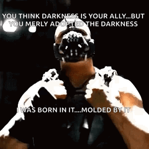 Bane From The Dark Knight Rises Is Wearing A Mask And Holding A Gun In His Hand . GIF