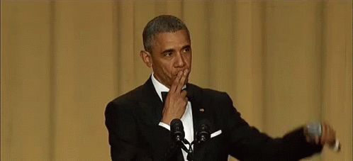 Barack Obama Is Giving A Speech In Front Of A Microphone While Covering His Mouth With His Hand . GIF