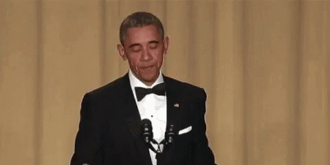 Barack Obama Is Holding A Microphone And Covering His Mouth . GIF