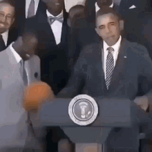 Barack Obama Is Standing At A Podium Giving A Speech While Holding A Basketball . GIF