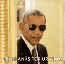 Barack Obama Is Wearing Sunglasses And A Suit And Tie While Standing In Front Of A Picture Frame . GIF
