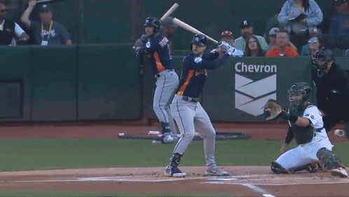 Baseball Player Swinging at Pitch Before Chevron Sign