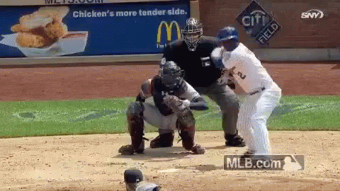 Baseball Player Swinging Bat At Ball In Front Of Crowd GIF