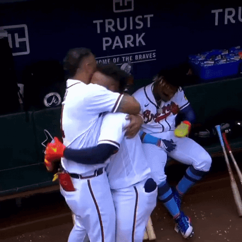 Baseball Players Hugging Each Other In Front Of A Sign That Says Truist Park GIF