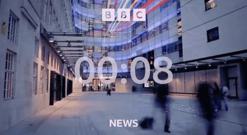 BBC News Screen With People Walking Past Building