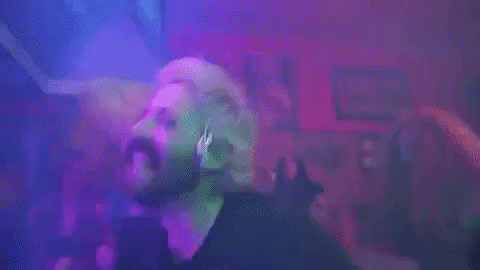 Bearded Man Dancing in Club in Front of Purple Lights