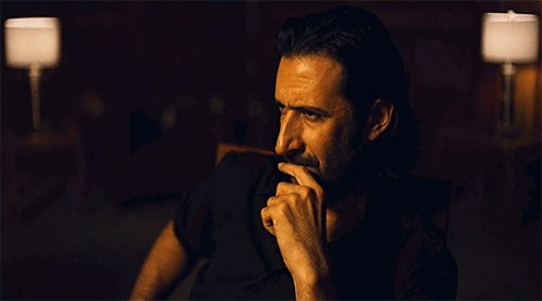 Bearded Man Hand on Chin in Dark Room