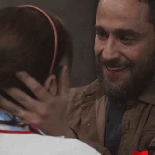 Bearded Man Hugging Another In Dark Room GIF