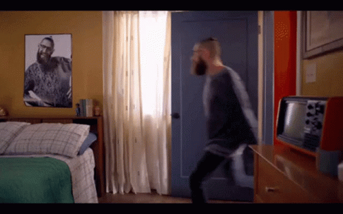 Bearded Man in Bedroom With Picture of Man on Wall