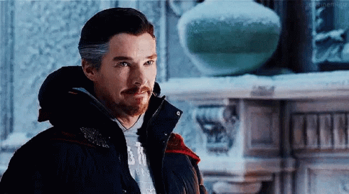 Bearded Man in Black Jacket by Fireplace in Snow