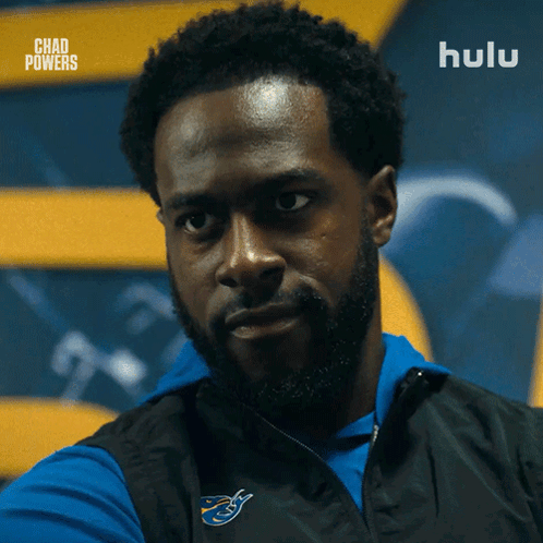 Bearded Man in Blue Shirt and Black Vest Saying Hulu