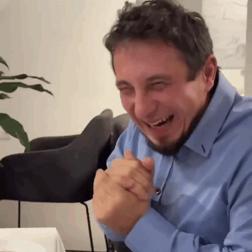 Bearded Man in Blue Shirt Laughing Hands Folded