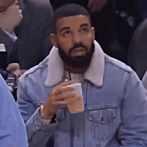 Bearded Man in Denim Jacket Holding Coffee in Crowd