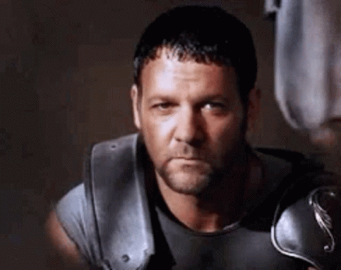 Bearded Man in Gray Shirt and Armor Looking at Camera