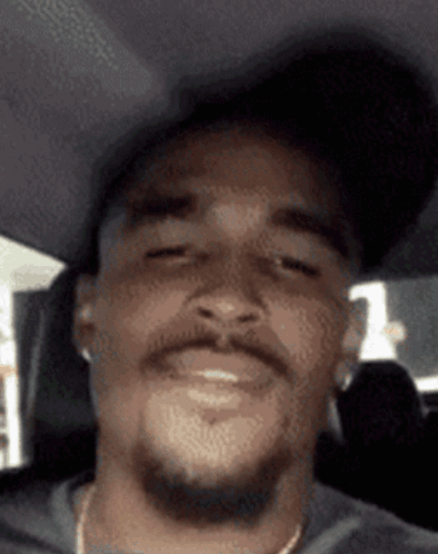 Bearded Man in Hat and Earbuds Smiling in Car