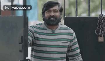 Bearded Man in Striped Shirt Smiling at Gate