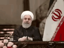 Bearded Man In White Hat At Table With Flag GIF