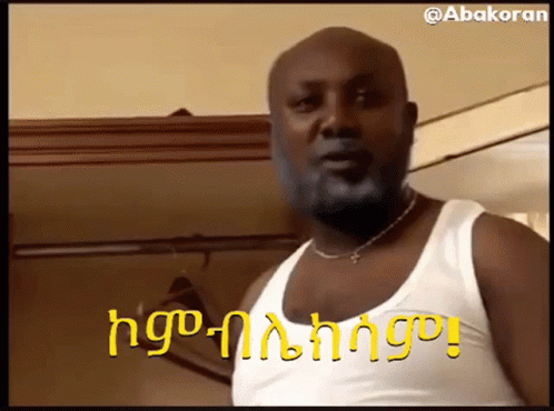 Bearded Man In White Tank Top And Necklace Beside Closet GIF