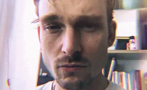 Bearded Man Looking At Camera Bookshelf GIF