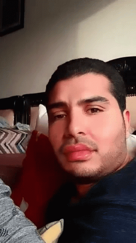 Bearded Man Looking at Camera on Bed