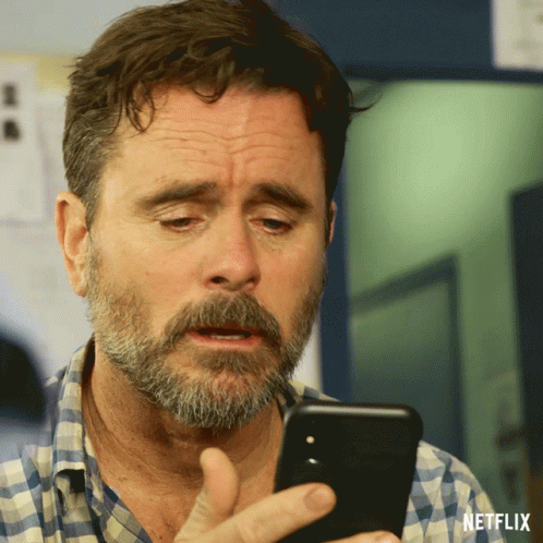 Bearded Man Looking at Phone With Netflix Logo