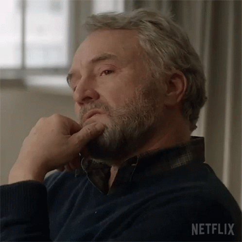 Bearded Man on Couch Hand on Chin Netflix Logo