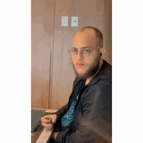 Bearded Man Sitting at Desk with Laptop and Cigarette
