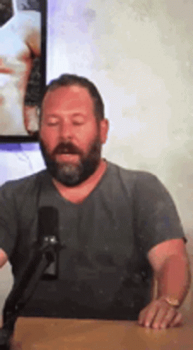 Bearded Man Sitting at Table with Microphone