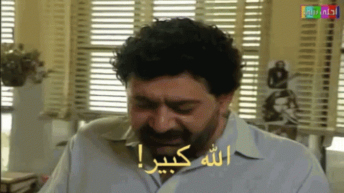 Bearded Man Sitting by Window with Arabic Writing