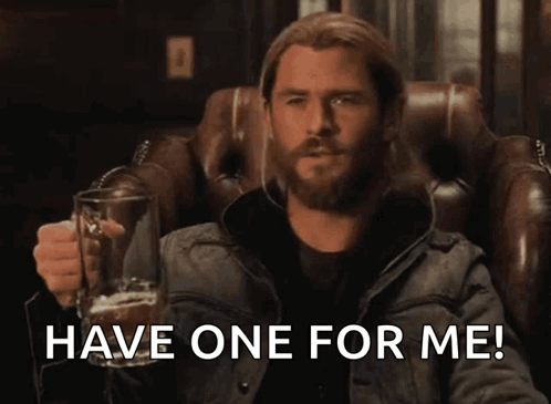 Bearded Man Sitting in Chair Holding Glass With Have One for Me