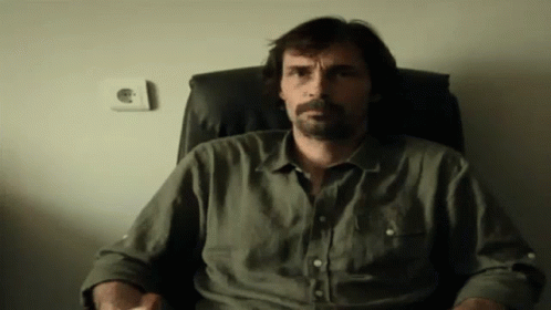 Bearded Man Sitting In Chair With Hands In Pockets GIF