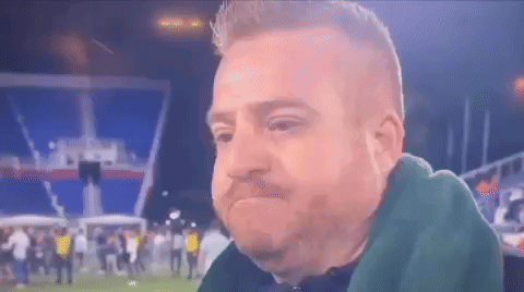 Bearded Man Sitting In Front Of Crowd On Soccer Field GIF