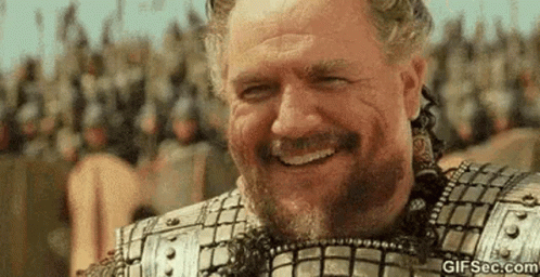 Bearded Man Smiling Before Armored Crowd GIF