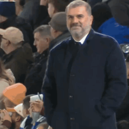 Bearded Man Standing in Crowd With Hands in Pockets