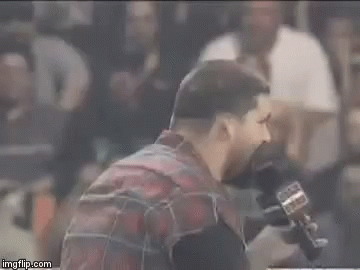Bearded Man Talking Into Microphone in Crowded Stadium