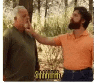 Bearded Man Touching Another Man's Nose in Forest