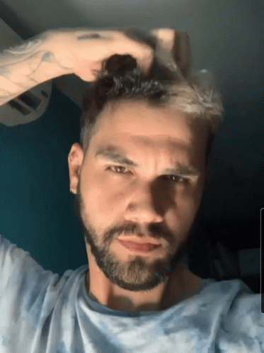 Bearded Man Touching Hair Looking At Camera GIF