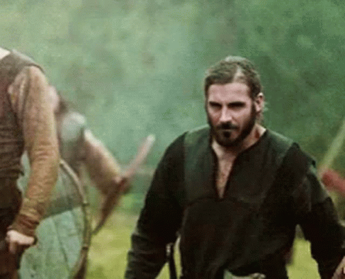 Bearded Man Walking with Sword in Field