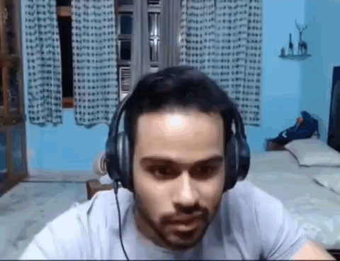 Bearded Man Wearing Headphones Sitting in Bedroom