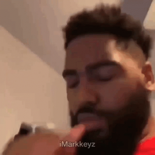 Bearded Man With Finger to Mouth Looking at Phone
