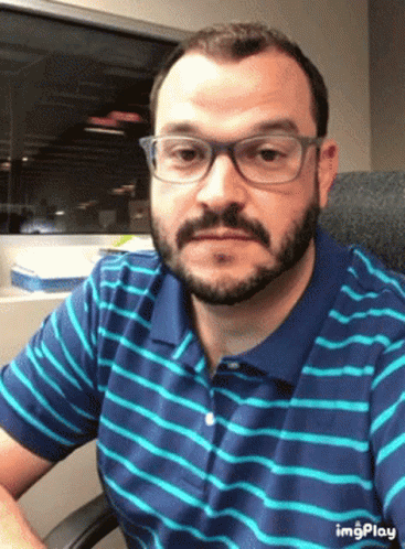 Bearded Man with Glasses and Striped Shirt Sitting