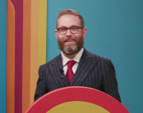 Bearded Man With Glasses Smiling At Podium GIF