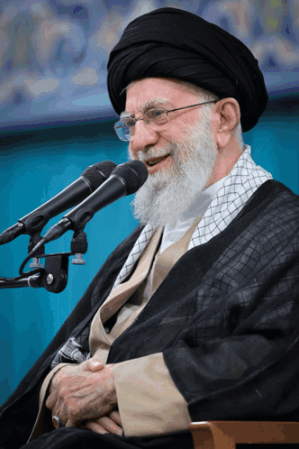 Bearded Man With Glasses Smiling Into Two Microphones GIF