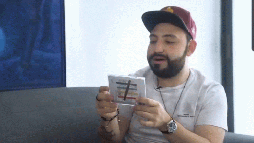 Bearded Man With Hat And Watch Holding CD GIF