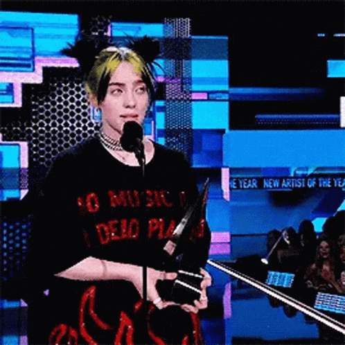 Billie Eilish Is Holding A Trophy And Speaking Into A Microphone At A Awards Show . GIF