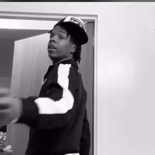 Black And White Man In Hat And Jacket Standing In Front Of Door GIF