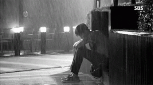 Black And White Man Sitting In Rain Head Down GIF