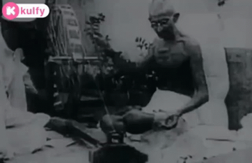 Black And White Man Sitting On Ground With Broom GIF