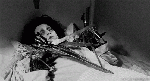 Black and White Person in Bed With Scissors